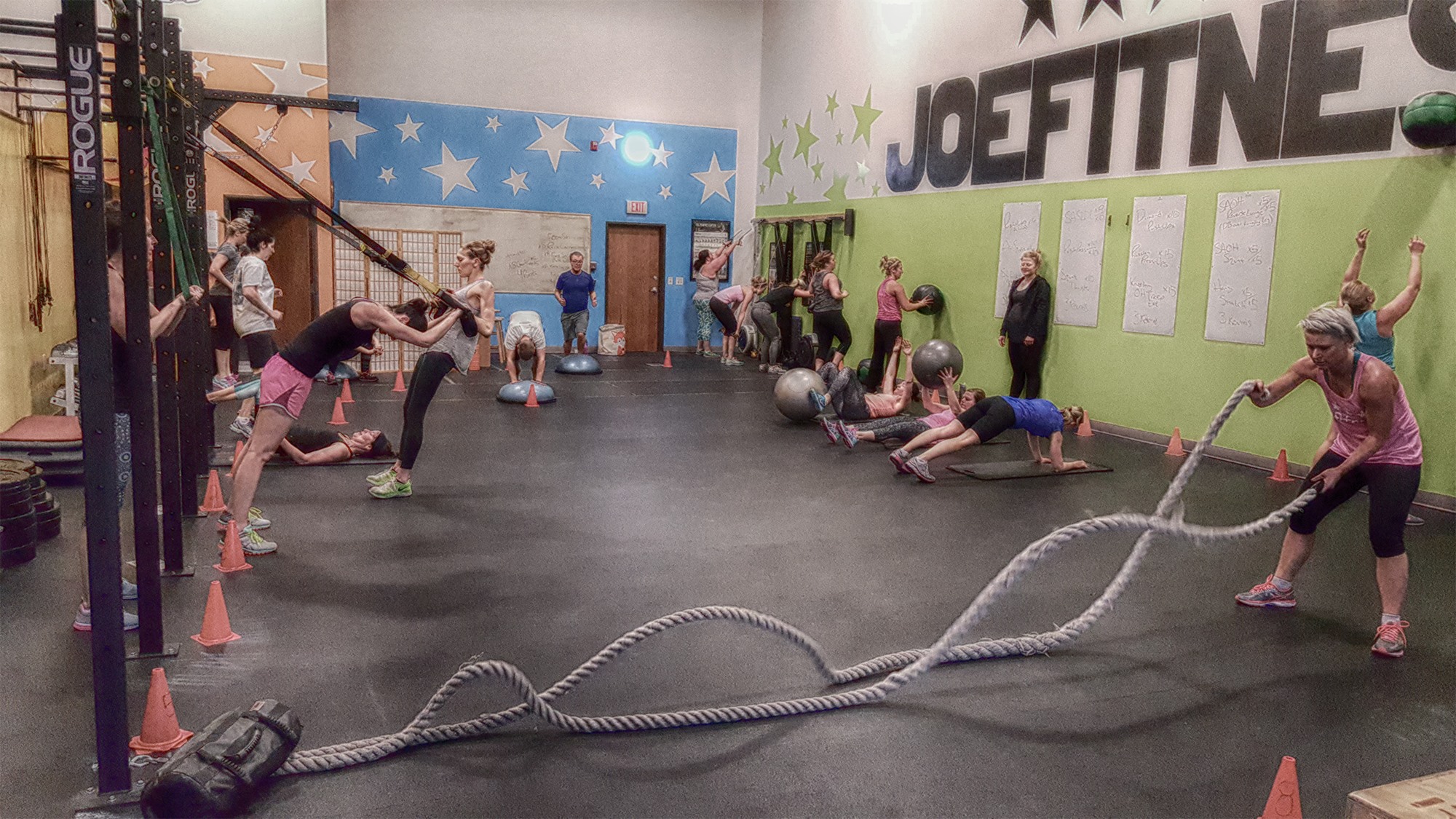 Picture of the joefitness bootcamp with members doing barbell, TRX, and body weight exercises.